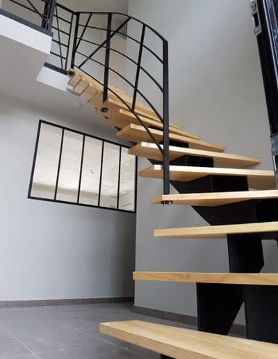 escalier en bois au premier plan et fenêtre métallique au second plan : ouvrages de métallerie et de serrurerie